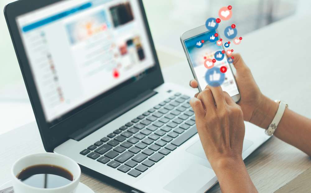 holding a mobile cell device to like posts by businesses using their social media management services to increase engagement