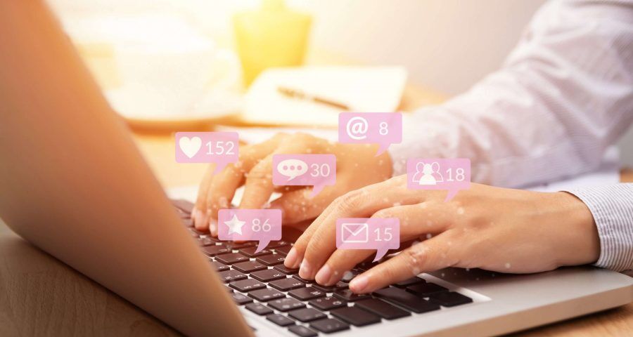 man typing on computer with social media engagement popping up on the keys