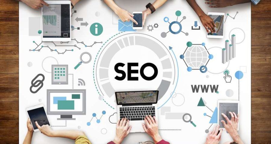 business workers sitting around conference table on digital mobile and desktop laptop devices using seo digital marketing methods to promote their services and personal brand for networking to network with industries and partners