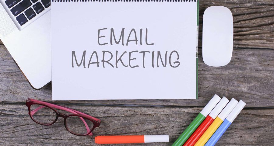 email marketing written on a notebook with glasses and markers next to it